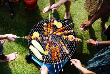 people putting kabobs on the grill