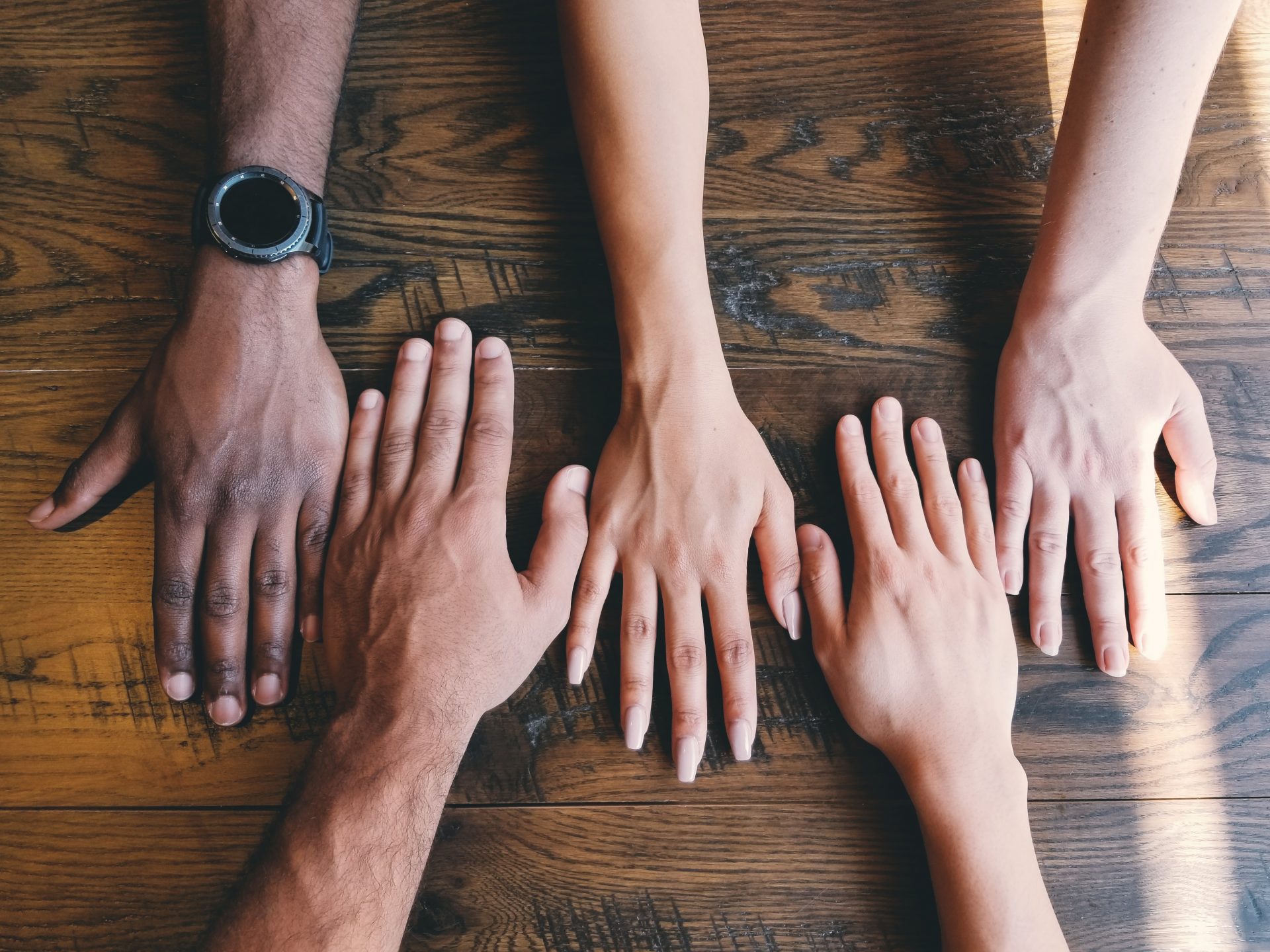 multiple ethnicities of people with their hands on a table