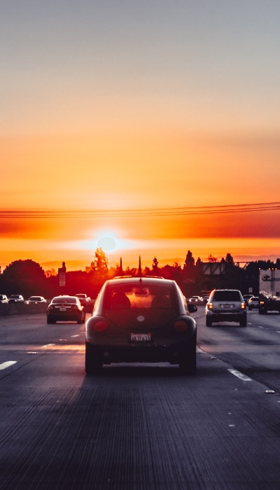 car driving into sunset